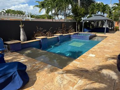 A modern backyard pool with blue tiles, palm trees, and a shaded gazebo.