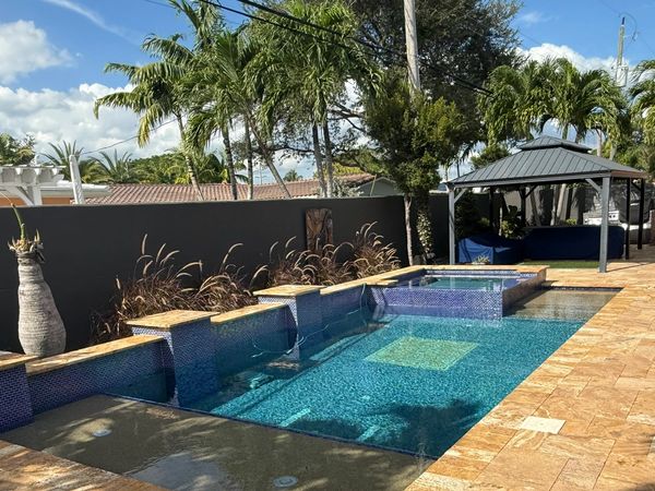 Modern backyard pool with spa and shaded seating area under a gazebo.