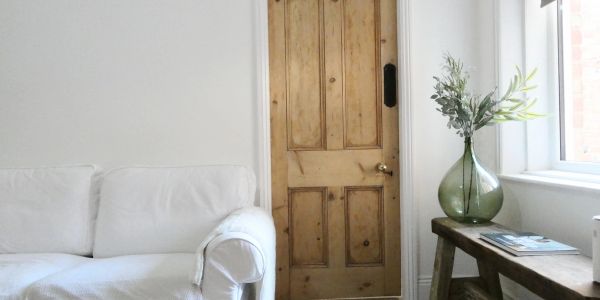 Minimalist living room corner with wooden door and white sofa.