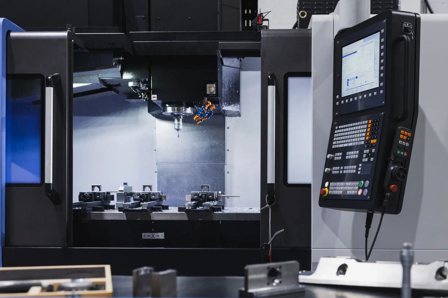 Modern CNC milling machine with control panel and metal workpieces inside.