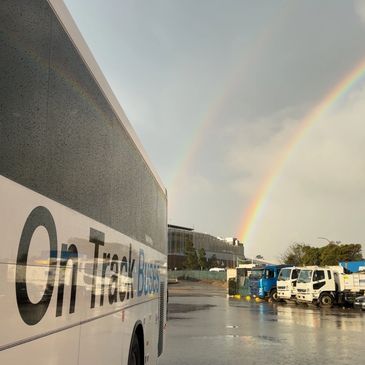 A double rainbow appears over a parking lot on a rainy day.