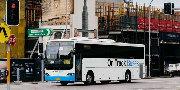 On Track Buses vehicle at an urban intersection with traffic lights and road signs.