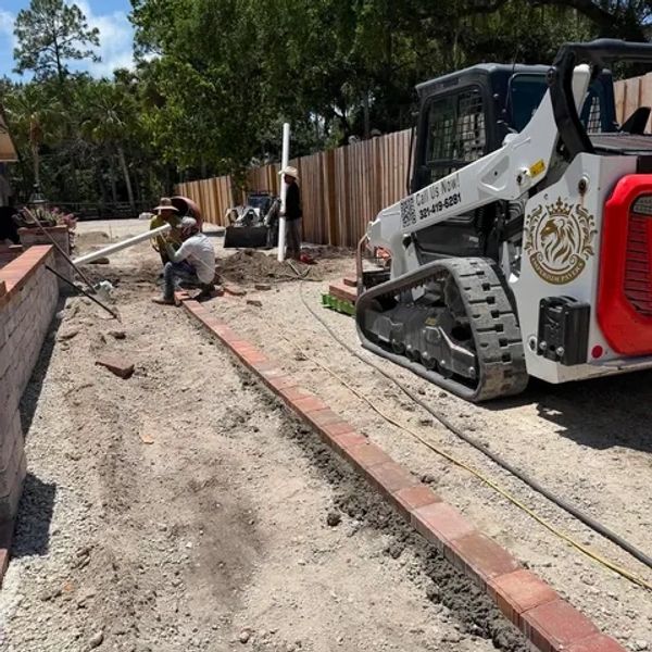 Construction workers laying bricks and using heavy machinery outdoors.