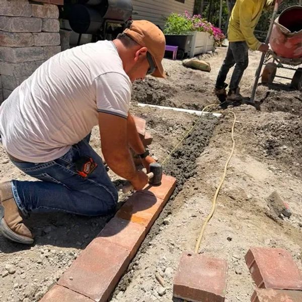 Man laying bricks to build a pathway outdoors.