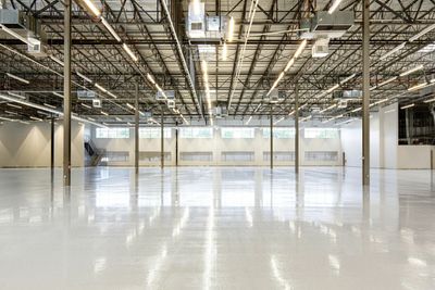 Spacious empty industrial warehouse with polished floors and exposed ceiling.