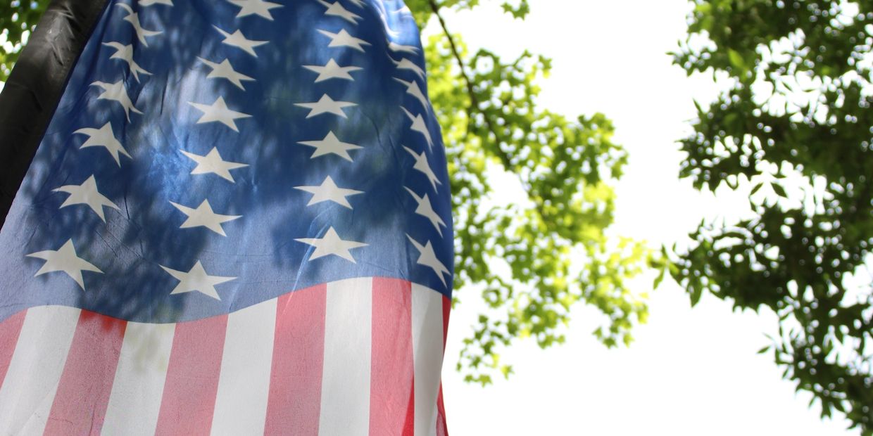 Close-up of the American flag with trees in the background.