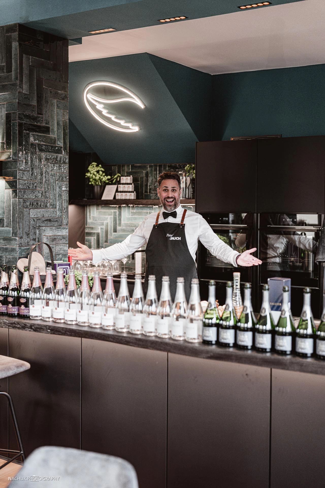 Peter Jauch steht hinter einer Reihe von Champagnerflaschen nach einem Tasting-Event.