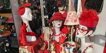 Vintage accessories and mannequins in red-themed display window.