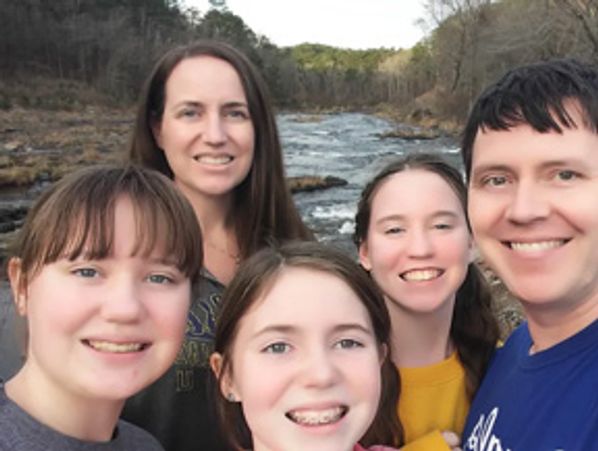 Family selfie by a river in nature.