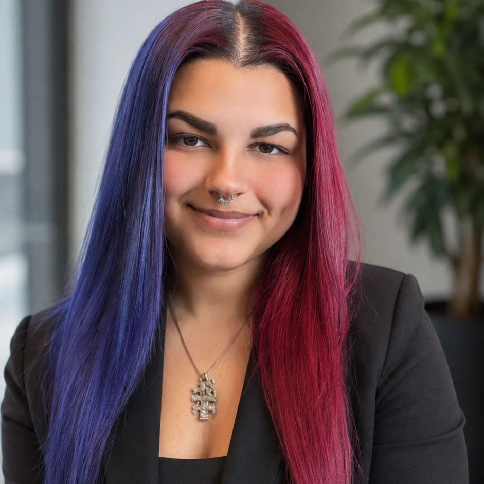 Woman with half purple and half pink hair smiling indoors.