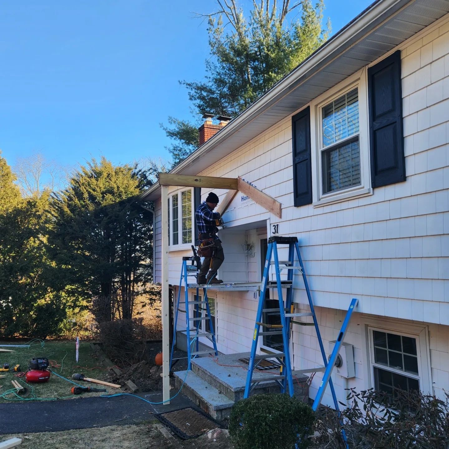 Worker patching and repairing the exterior siding of a house, using tools to fix damaged areas.