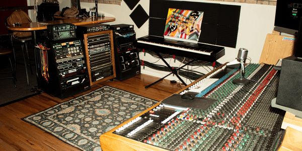 A professional music studio with mixing console, keyboard, and audio equipment.