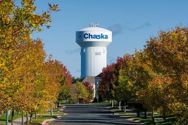 Water tower labeled 'Chaska' surrounded by colorful autumn trees.