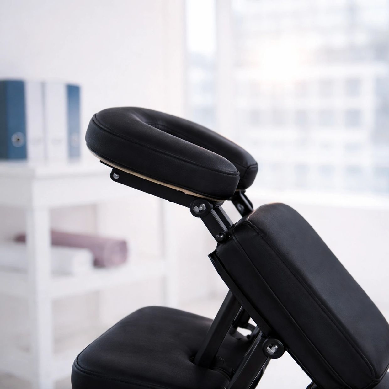 Close-up of a black padded chair in a bright room.
