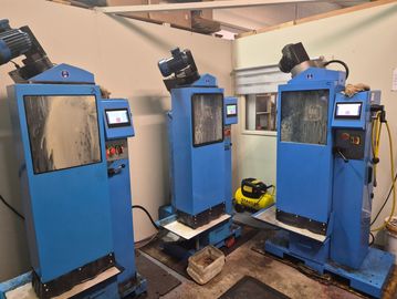 Three blue industrial machines with control panels in a workshop.