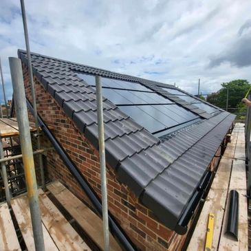 Crest double pan concrete roof tiles with integrated solar panel system. Cloaked verge tiles