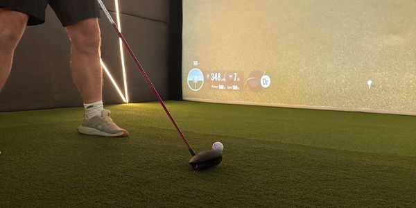 Man preparing to hit a golf ball indoors with a virtual golf simulator.