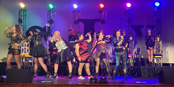 A group of women performing on stage with colorful lights.