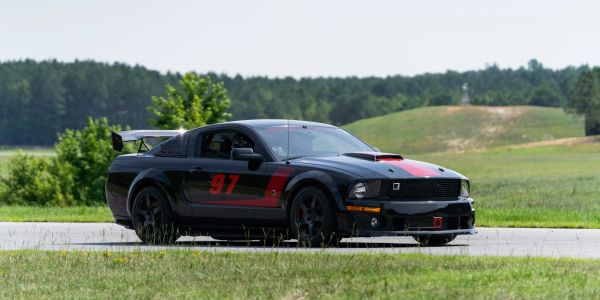 Black sports car with red accents and number 97 on a race track.