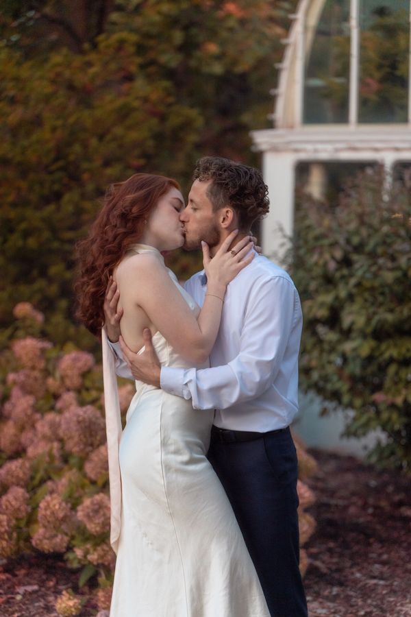 Couple kissing outdoors in wedding attire.