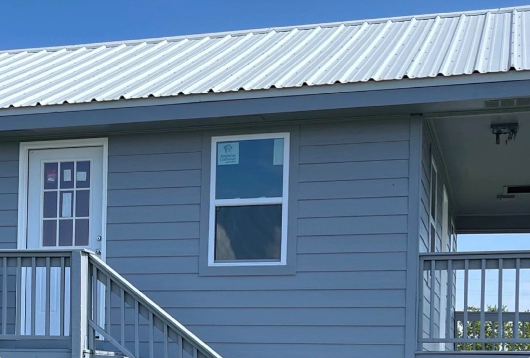 Modern house exterior with gray siding and metal roof.