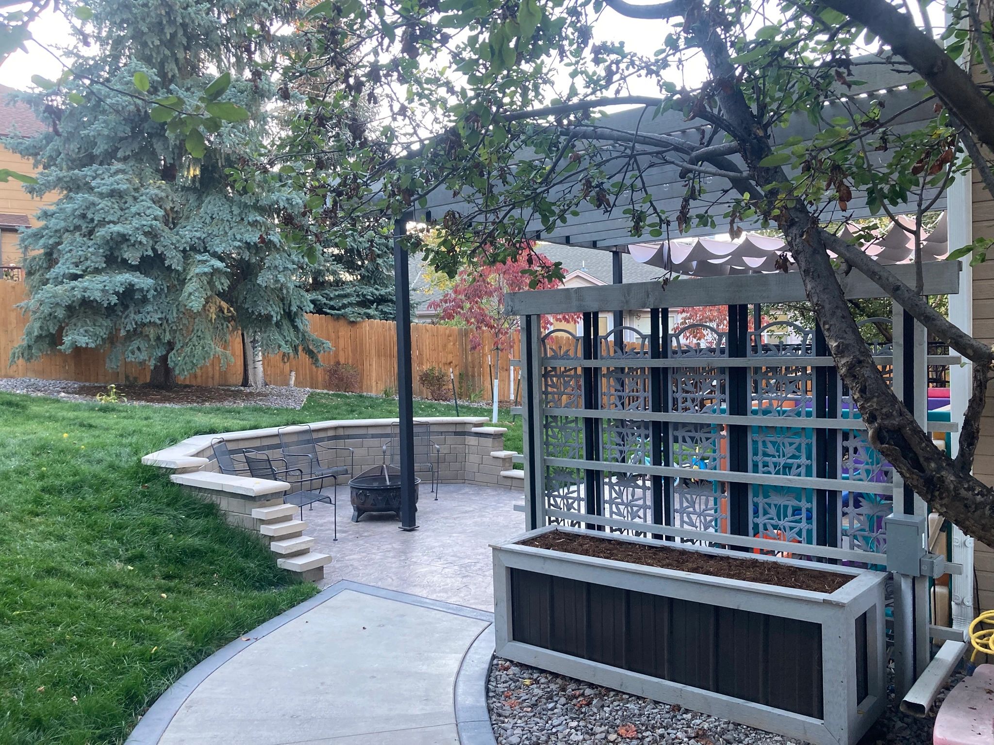 Cozy backyard with fire pit and pergola seating area.