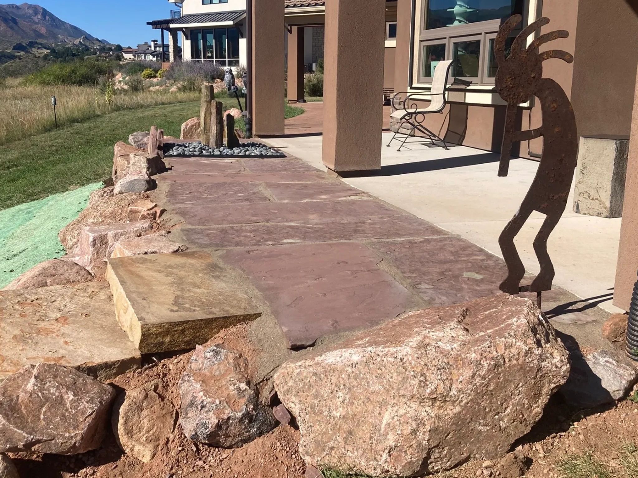 Rustic outdoor patio with stone walkway and metal sculpture.