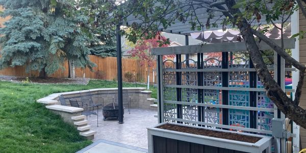 Cozy backyard patio with stone seating area and metal chairs.