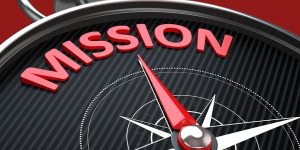 Close-up of a compass pointing to the word 'MISSION' in red letters.