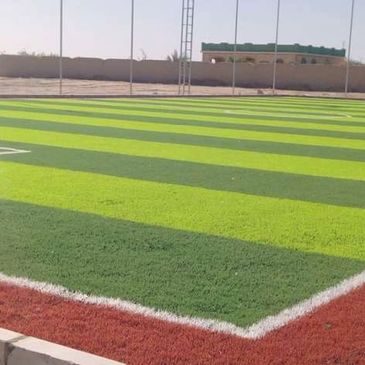 Striped green artificial turf field with a red border.