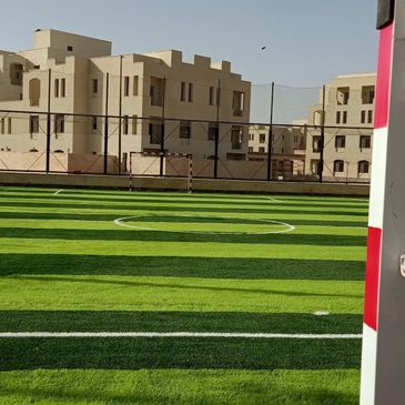 Empty outdoor soccer field with buildings in the background.