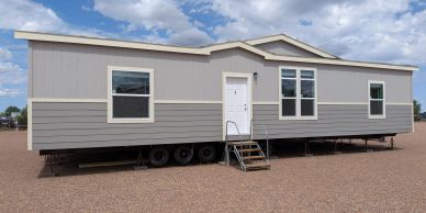 Single-story gray mobile home with multiple windows.