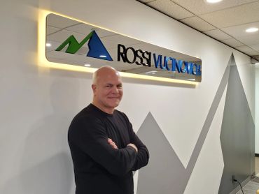 Man standing with arms crossed near a Rossi Valvoline sign.