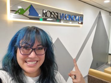 Person smiling and pointing at a Rossi Vueno sign.