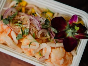 Shrimp salad with sliced onions and edible flower garnish.