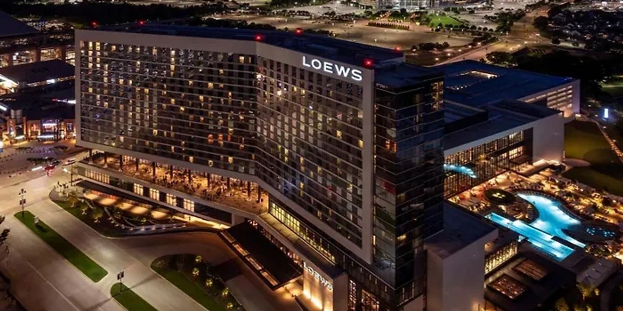 Night view of the illuminated Loews hotel with a glowing pool area.