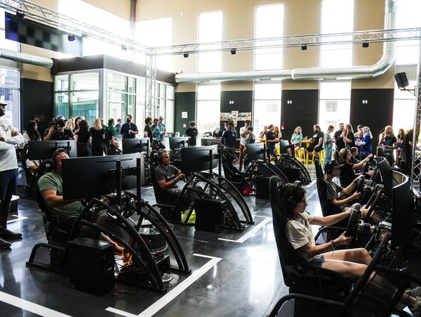 People engaged in a competitive racing simulator event in a modern gaming space.