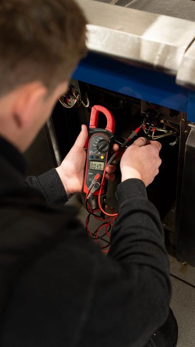Technician using a clamp meter to check electrical connections.