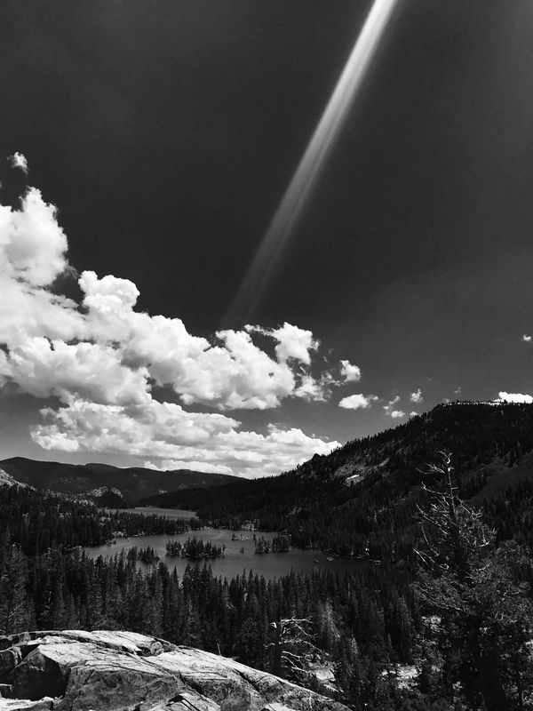 Black and white mountain landscape with a lake and dramatic clouds.