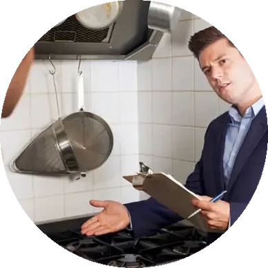 Man in suit inspecting kitchen stove with clipboard.