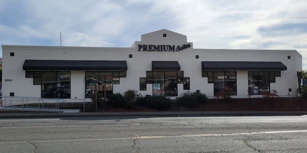 White building with black awnings labeled PREMIUM Suites under a cloudy sky.