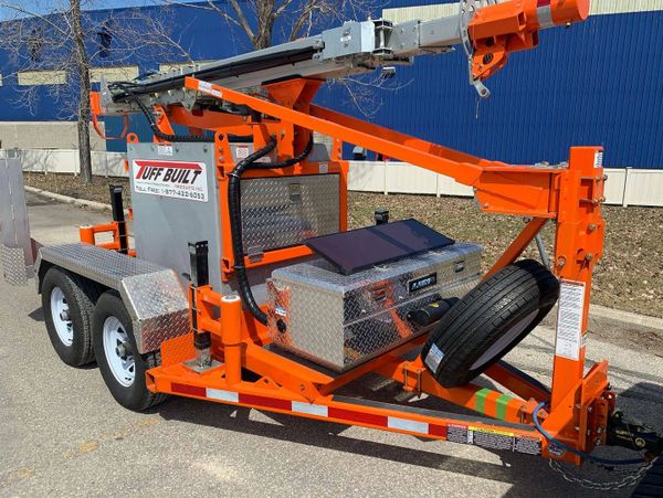 Orange utility trailer with equipment and spare tire parked outside.
