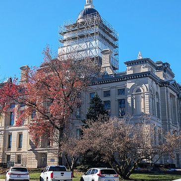 Historic courthouse building with autumn trees and clear blue sky.