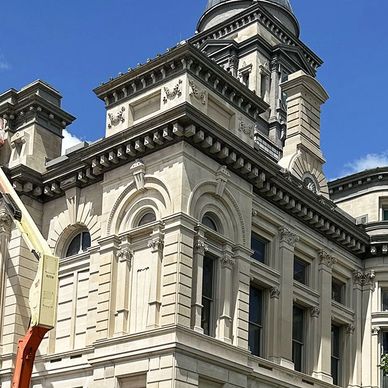 Historic beige stone building with detailed architectural features under a clear blue sky.