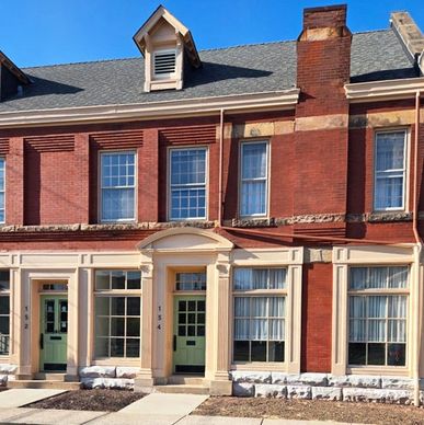 Historic red brick townhouse with green door and large windows.