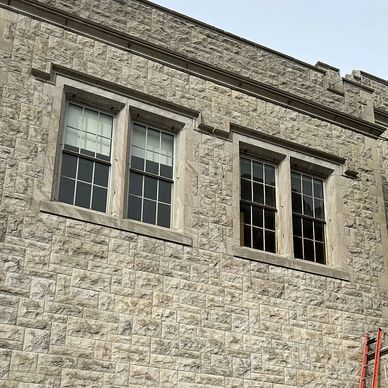 Stone building wall with two windows and a red ladder.