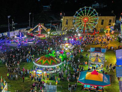 A lively nighttime carnival with illuminated rides and crowds of people.