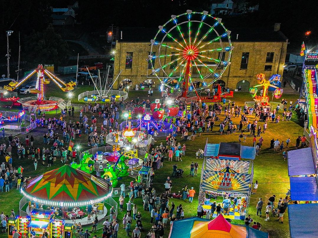 A vibrant night carnival with colorful rides and crowds of people.