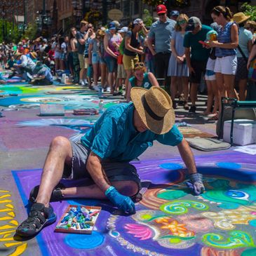 artist works on chalk drawing with festival attendees watching