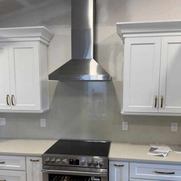 Modern kitchen with stainless steel stove and white cabinetry.